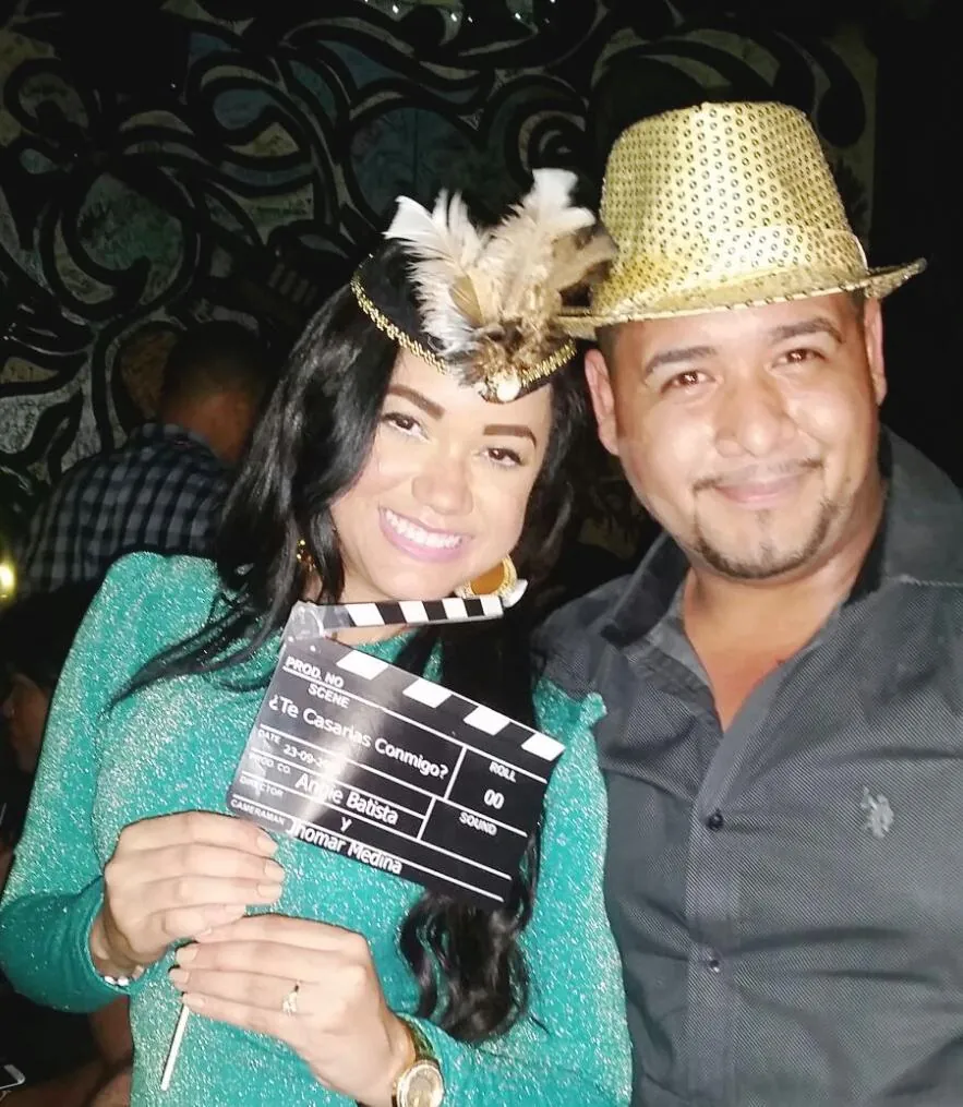 Angie con una claqueta que pregunta: ¿Te casas conmigo?, junto a Jhomar